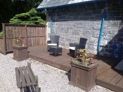 a wooden deck with chairs and flowers in pots at Ardwell House East Lodge in Stranraer