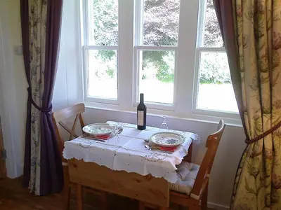 a dining room table with a bottle of wine on it at Ardwell House East Lodge in Stranraer