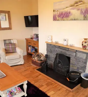 a living room with a stone fireplace and a table at Ardwell House East Lodge in Stranraer