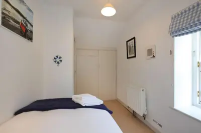 a white bedroom with a bed and a window at Allonby Cottage in Kippford