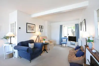 a living room with blue chairs and a tv at Allonby Cottage in Kippford