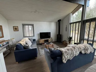 a living room with two blue couches and a tv at Fig Tree Lodge in Ellonby