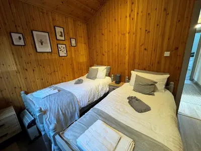 two beds in a room with wooden walls at Fig Tree Lodge in Ellonby