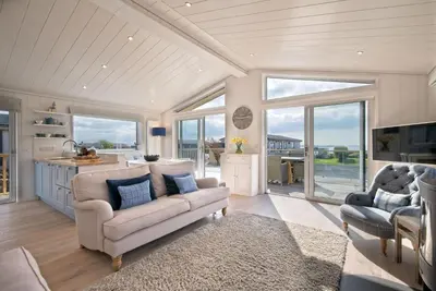 a living room with a couch and a kitchen at Bluebell Lodge in Girthon