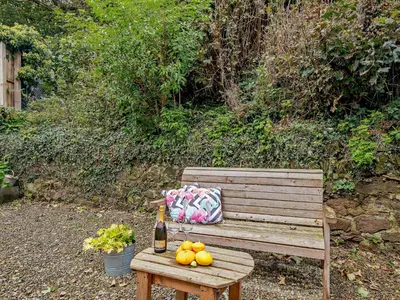 a wooden bench with a bottle of wine and fruit on it at 1 Bed in Maybole 93562 in Maybole