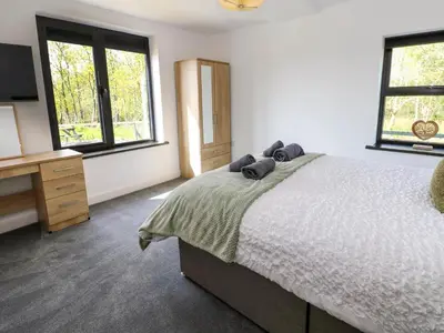 a bedroom with a bed and a desk and windows at Oaktree Cottage - 3 Bedrooms - Sleeps 6 in Frizington