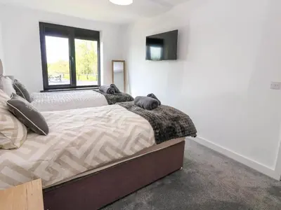 a bedroom with two beds and a tv on the wall at Oaktree Cottage - 3 Bedrooms - Sleeps 6 in Frizington