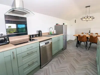 a kitchen with green cabinets and a wooden table at Sycamore Cottage - 2 Bedrooms - Sleeps 4 in Frizington