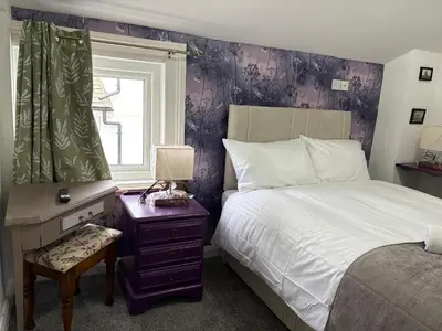 a bedroom with a bed and a window and a table at Athol House in Douglas