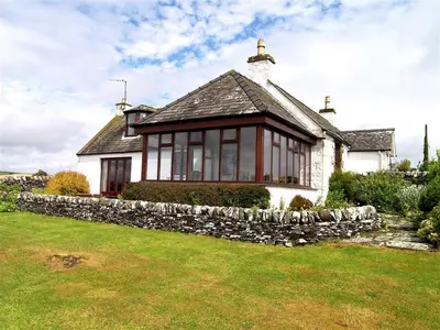 a house with a stone wall in front of it at Allanhead Cottage in Kirkcudbright