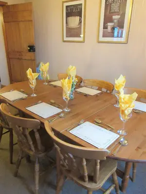 a wooden table with chairs and glasses on it at Allanhead Cottage in Kirkcudbright