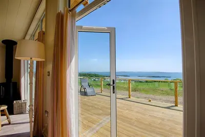 a door to a balcony with a view of the ocean at Barley Lodge in Girthon