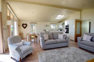 a living room with couches and chairs and a kitchen at Barley Lodge in Girthon