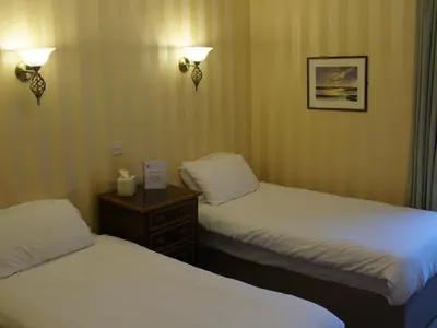 a hotel room with two beds and a table with a sign at Corner House Hotel in Annan