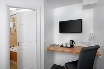 a room with a desk with a television and a chair at Corner House Hotel in Annan