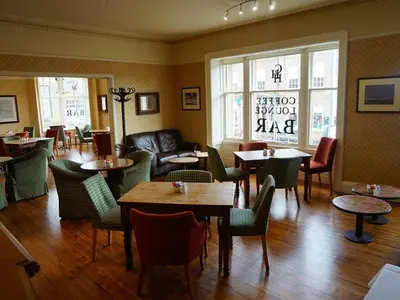 a restaurant with tables and chairs and a couch at Corner House Hotel in Annan