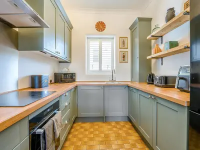 a kitchen with blue cabinets and wooden counter tops at Piersland Mews in Troon