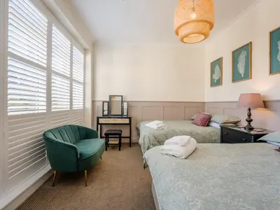 a bedroom with two beds and a chair and a desk at Piersland Mews in Troon