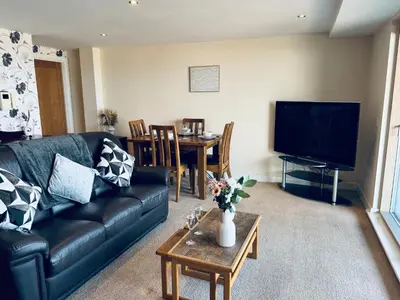 a living room with a black leather couch and a table at Pears Suite - 1 Bedroom - Sleeps 2 in Whitehaven
