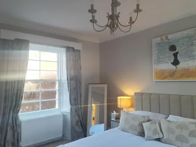 a bedroom with a bed and a window and a chandelier at Park Cottage - Spacious & Luxurious Room in B Listed Cottage in Moffat