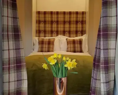 a vase with yellow daffodils in front of a bed at Lake District, Mountain Views, Accessible Studio Bothy in Borrowdale Valley