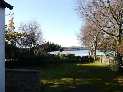 a yard with a view of a lake and trees at Calluna Cottage in Rockcliffe