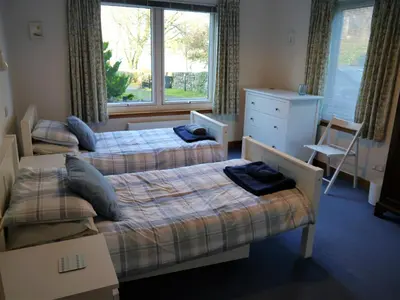 two twin beds in a room with a window at Calluna Cottage in Rockcliffe