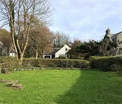 a yard with green grass and a house and trees at Calluna Cottage in Rockcliffe
