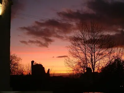 a sunset with a tree in front of a building at Bedroom 2 - Rockcliffe in Dumfries