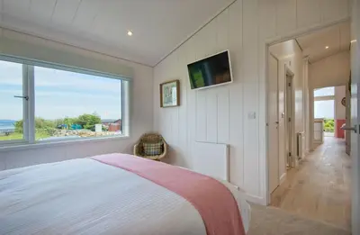 a bedroom with a bed and a large window at Clover Lodge in Gatehouse of Fleet