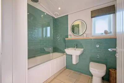 a bathroom with a tub and a sink and a toilet at Clover Lodge in Gatehouse of Fleet