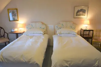 two beds in a room with two tables and two lamps at Craigrathan in Kippford