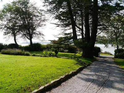 a road leading to a field of grass with trees at Craigrathan in Kippford