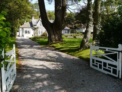 a driveway with a white fence and a house at Craigrathan in Kippford