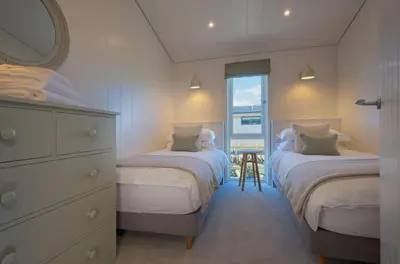 a bedroom with two beds and a dresser and a window at Crabtree Lodge in Girthon