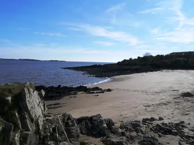 a beach with rocks and the ocean on a sunny day at Crabtree Lodge in Girthon