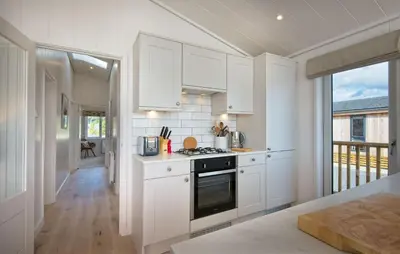 a kitchen with white cabinets and a stove at Crabtree Lodge in Girthon