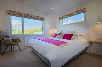 a bedroom with a large bed and two windows at Crabtree Lodge in Girthon