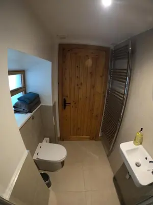 a bathroom with a toilet and a sink and a wooden door at Holly Lodge, Gilchristland Organic Farm cottage in Closeburn