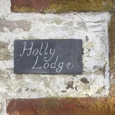 a sign on a brick wall with the words holly lodge at Holly Lodge, Gilchristland Organic Farm cottage in Closeburn