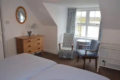 a bedroom with a bed and a table and a chair at Elm Cottage in Kippford