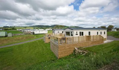 a modular home with a deck on a grass field at Konkers in Girthon