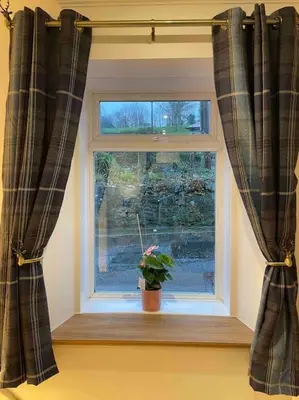 a window with a potted plant on a window sill at Modern cottage with hot tub in Kirkcudbright
