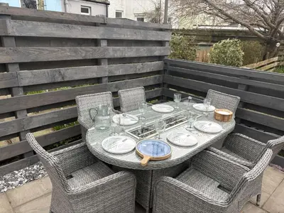 a table with chairs and plates on a patio at Modern cottage with hot tub in Kirkcudbright