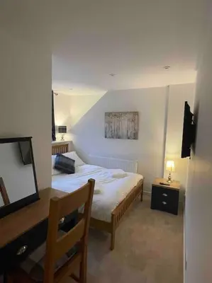 a bedroom with a bed and a desk and a television at Modern cottage with hot tub in Kirkcudbright