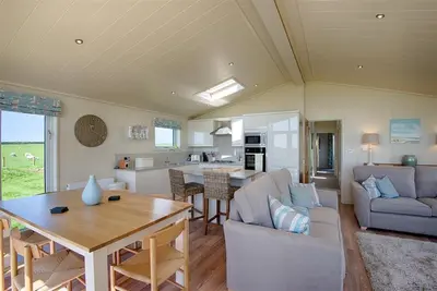 a living room with a couch and a table and a kitchen at Granary Lodge in Girthon