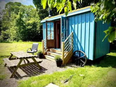 a blue tiny house with a picnic table and a chair at Highland Hideaway in Wigton