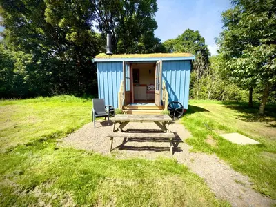 a blue shed with a picnic table and a chair at Highland Hideaway in Wigton