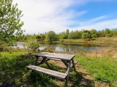 a wooden picnic table sitting next to a river at Silverbirch Cottage - 3 Bedrooms - Sleeps 6 in Frizington