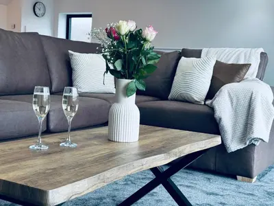 a vase of flowers on a coffee table with two wine glasses at Silverbirch Cottage - 3 Bedrooms - Sleeps 6 in Frizington